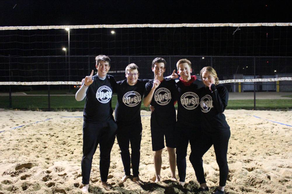 Students wearing championship shirts from an upper bracket sand volleyball tournament